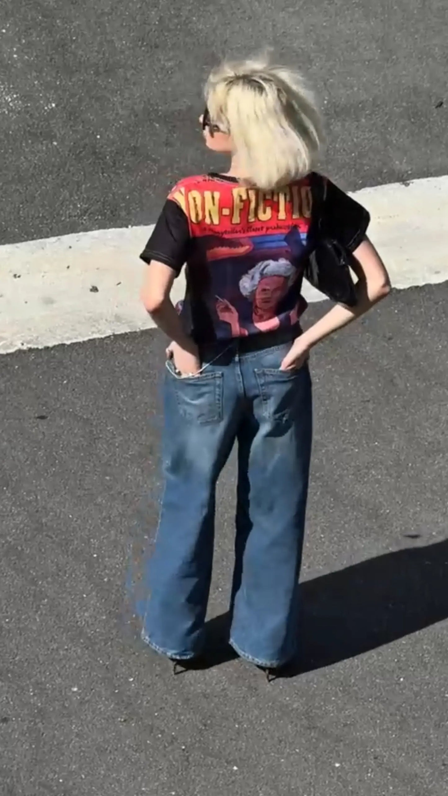 Person wearing a graphic t-shirt and blue jeans on a street